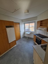 A kitchen with wooden cabinets, a window, a refrigerator, and an electric stove with an oven.