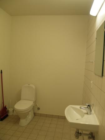 Bathroom with a toilet, wall-mounted sink, and tiled floor and walls.