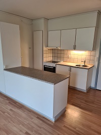 Modern kitchen area with white cabinets, a granite-look countertop, an oven, and a breakfast bar.