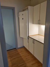 A compact kitchen area with white cabinets, a refrigerator, and a light-colored countertop.
