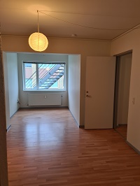 Empty room with hardwood floor, a large window showing an exterior staircase, and a white pendant light.