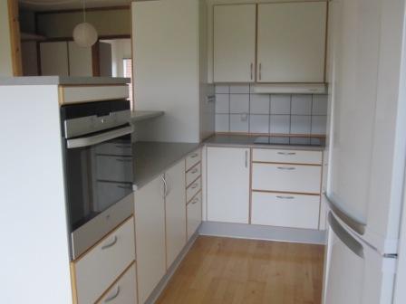 A photo of a modern kitchen with white cabinets and a built-in oven.