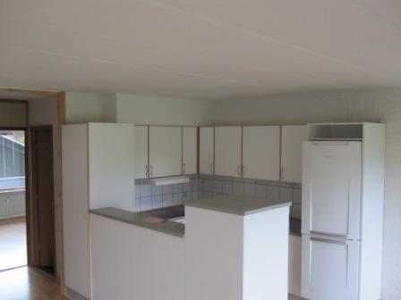 A photo of the kitchen area showing white cabinetry and a refrigerator.