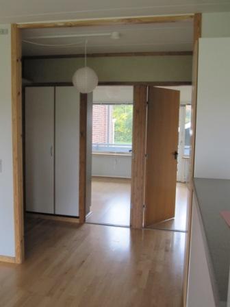 A photo of the entrance hallway with wooden floors and a white wardrobe.