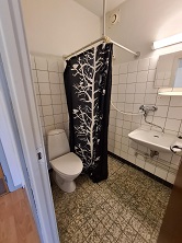 A small bathroom with a toilet, sink, and a black and white shower curtain.