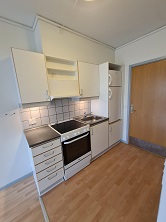 A compact kitchen area with white cabinets, an electric stove, and a refrigerator.
