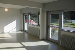 Bright, empty room with large windows and radiators, showing an outdoor view.