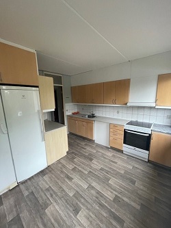 A kitchen with light wood cabinets, a white refrigerator, and a white stove, showing the opposite side of the kitchen from the previous view.