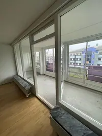 Foto di un soggiorno con pavimento in legno, finestre grandi e balcone