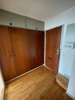 Entrance hall with wooden floors, a large built-in wooden wardrobe, and the front door.