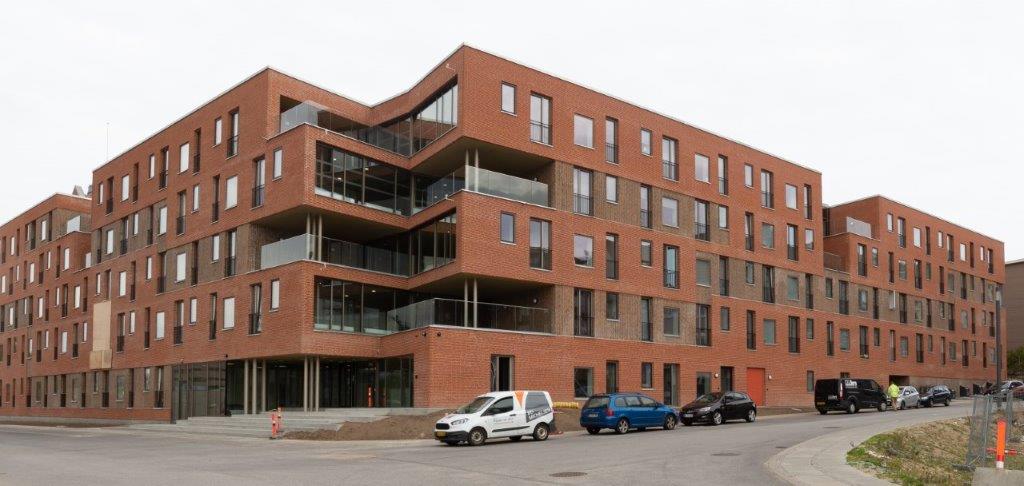 Rõdude ja pargitud autodega moodsa telliskivikorterelamu välisvaade.