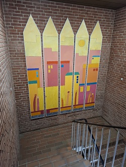 Stairwell with a colorful, abstract mural depicting a cityscape on a brick wall.